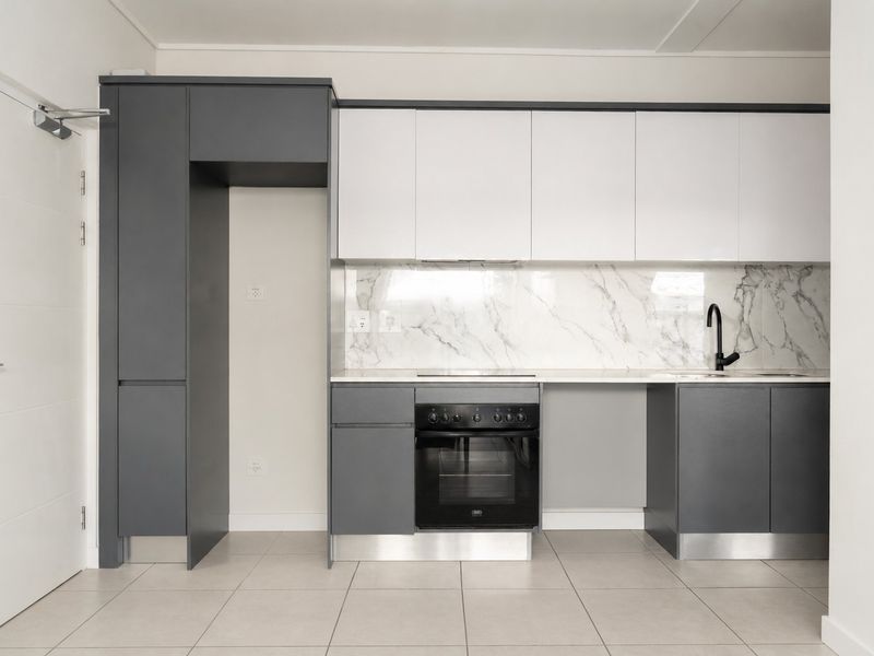 Modern kitchen featuring two-tone cabinetry, marble-look splashback, built-in oven, cooktop, and neutral tiled flooring in a clean, contemporary layout.