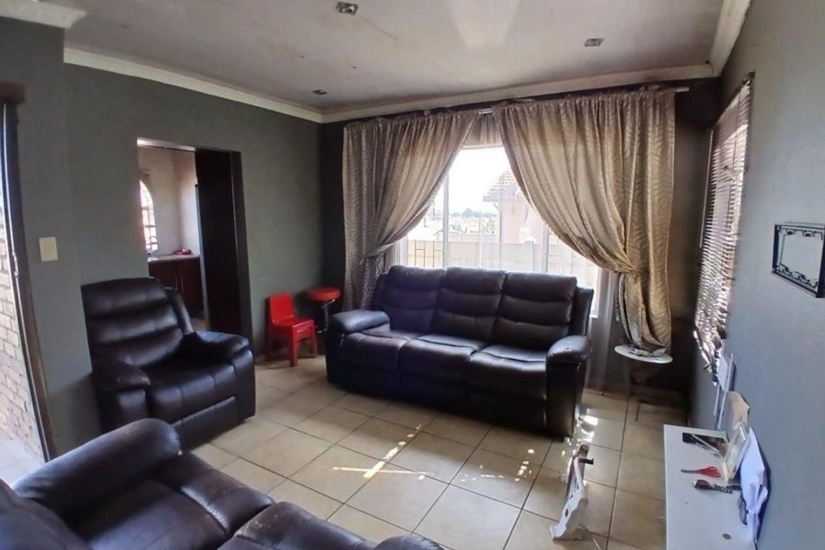 A living room featuring tiled flooring, recessed downlighting, and decorative cornicing, with visible signs of ceiling wear.