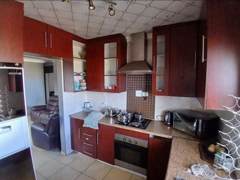 A functional kitchen featuring dark wood cabinetry, laminate countertops, a built-in oven with gas hob, and a tiled backsplash.