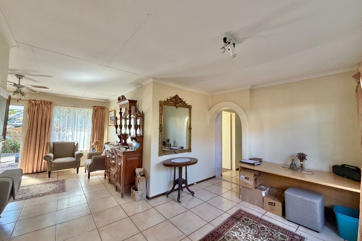 A spacious living area featuring ceramic floor tiles, a decorative archway, and a built-in desk, offering a functional layout with natural light.