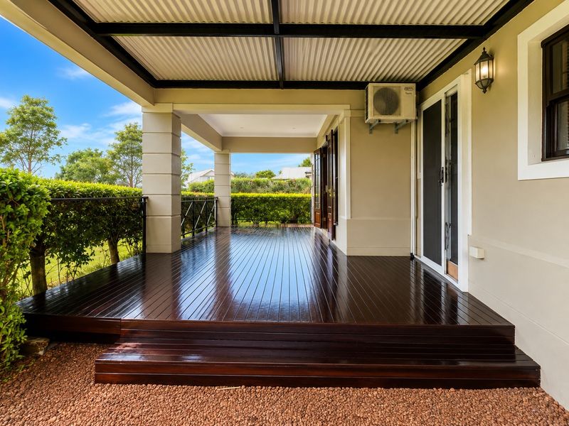 A spacious covered patio featuring polished timber decking, a corrugated roof, and direct access to the interior through sliding glass doors.