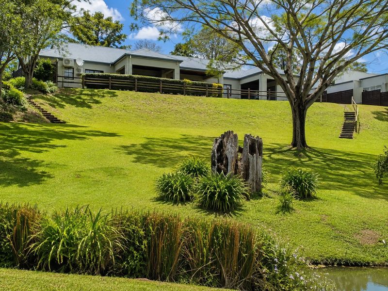 A view of the rear elevation of the townhouse, featuring a large landscaped lawn, timber fencing, and a covered patio area.