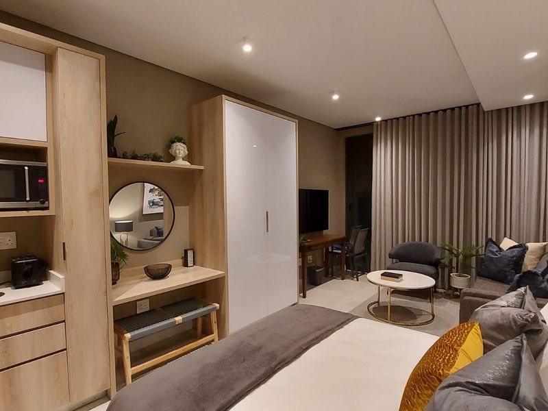 A modern, well-appointed bedroom featuring integrated cabinetry, a built-in vanity, recessed lighting, and floor-to-ceiling curtains, creating a cohesive and functional living space.