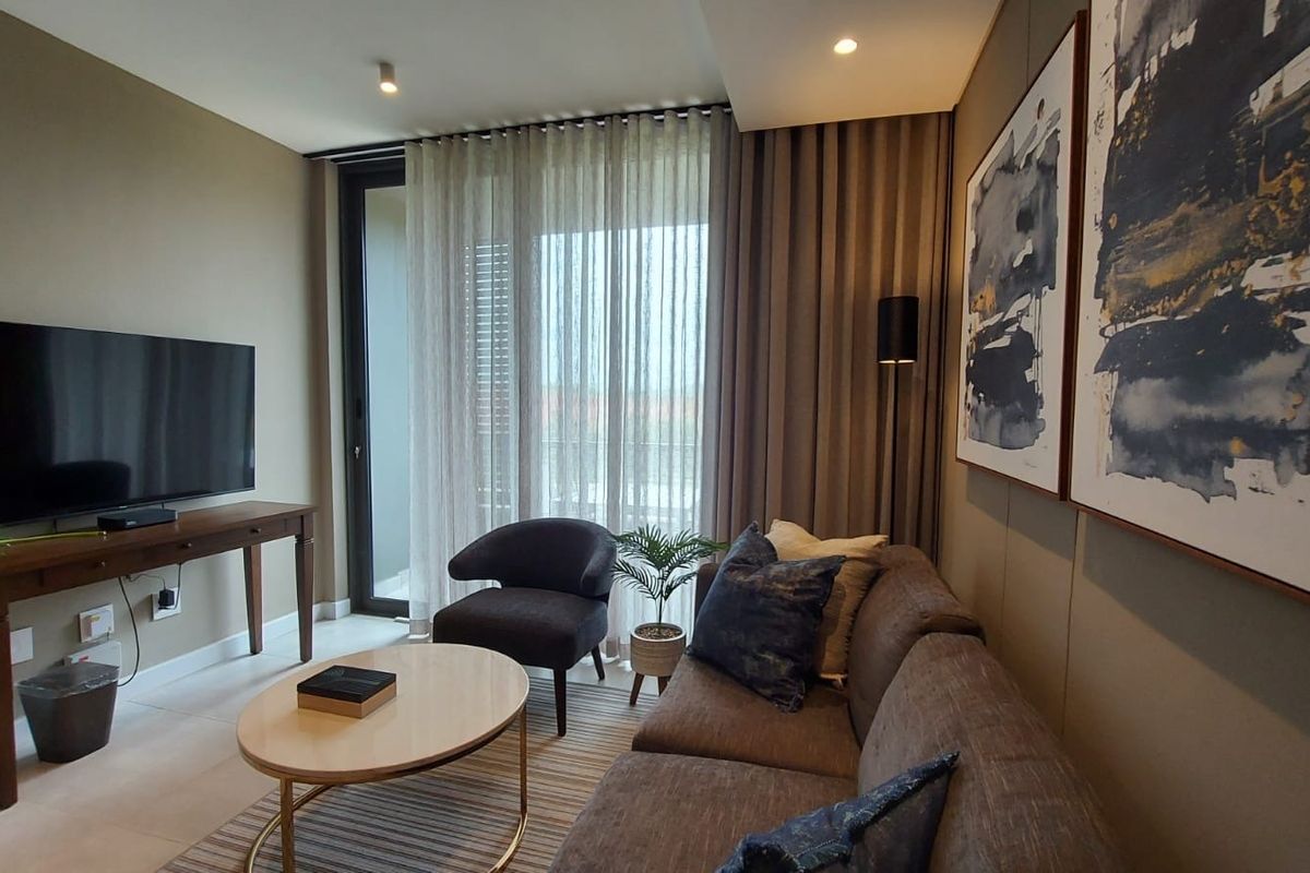A modern, well-maintained living room featuring neutral tones, recessed lighting, and a large sliding glass door providing access to the balcony.