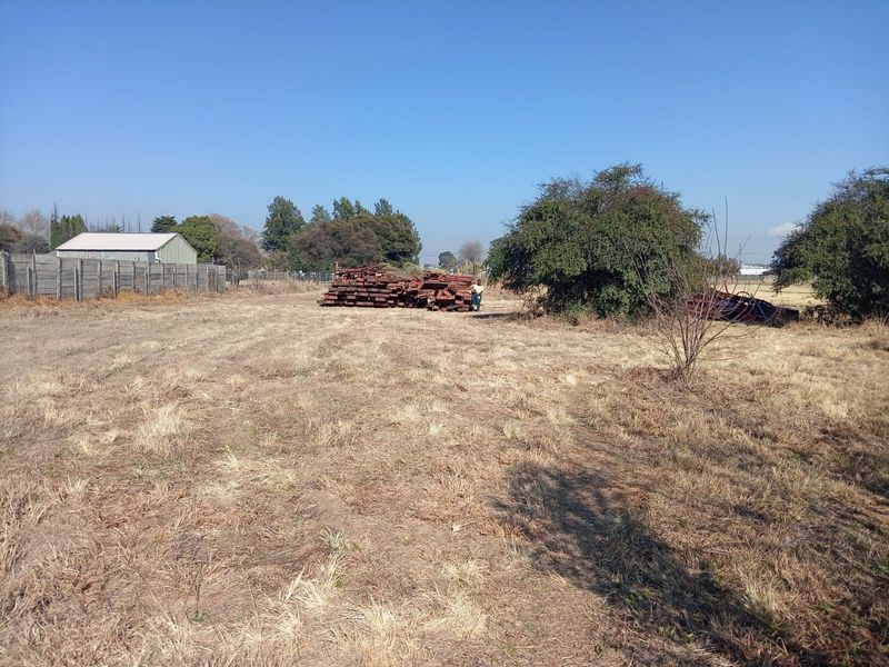 Expansive undeveloped land featuring a precast concrete boundary wall and a small metal storage shed in the background.