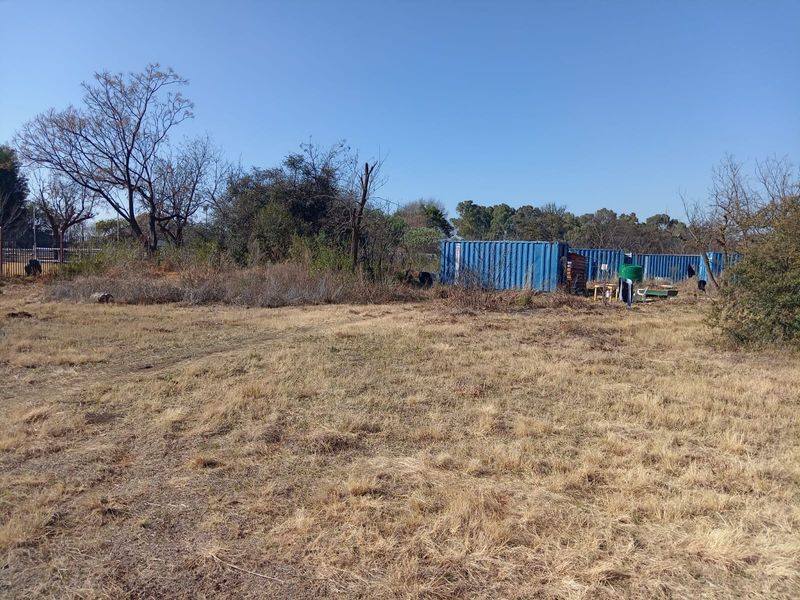 Expansive undeveloped land featuring several shipping containers and natural vegetation, offering potential for future development or storage use.