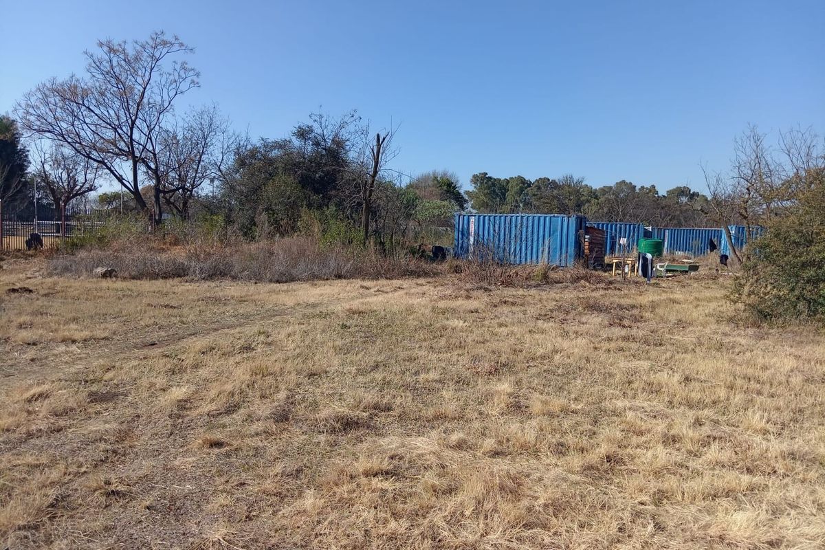 Expansive undeveloped land featuring several shipping containers and natural vegetation, offering potential for future development or storage use.