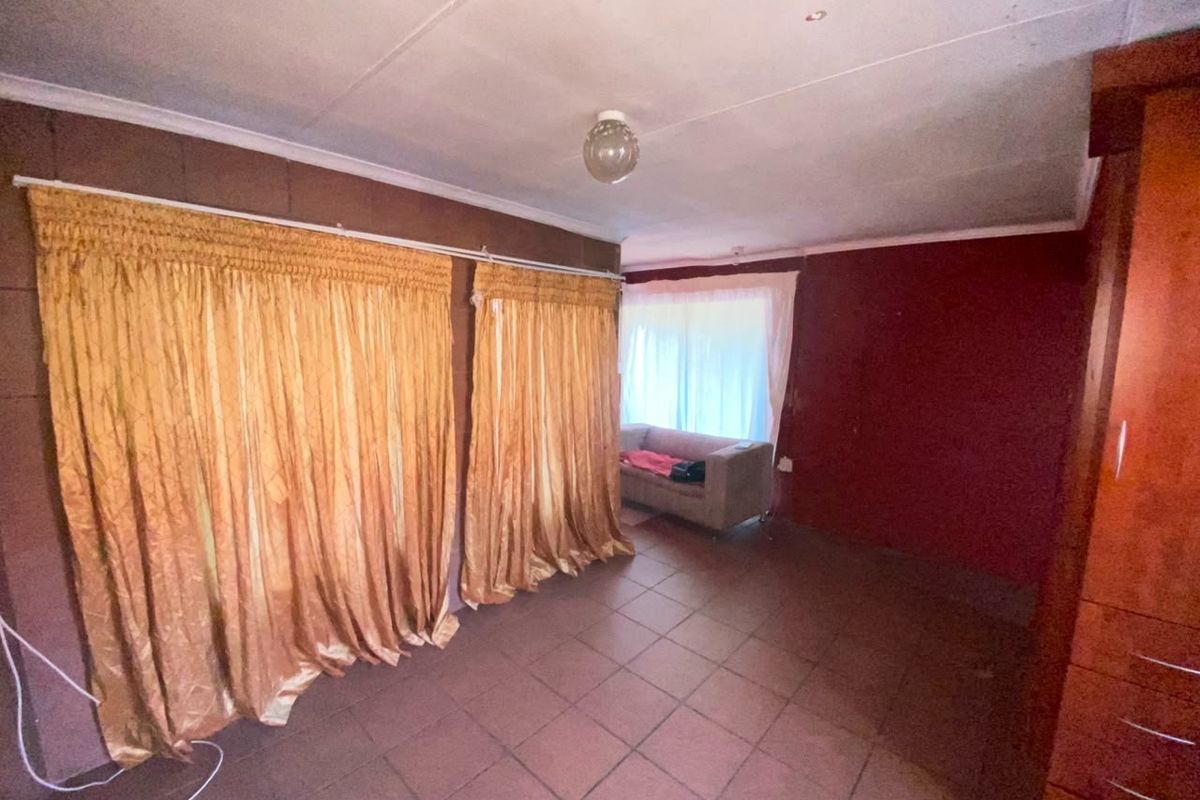 A bedroom featuring tiled flooring and built-in cupboards, currently requiring cosmetic updates to modernize the space.