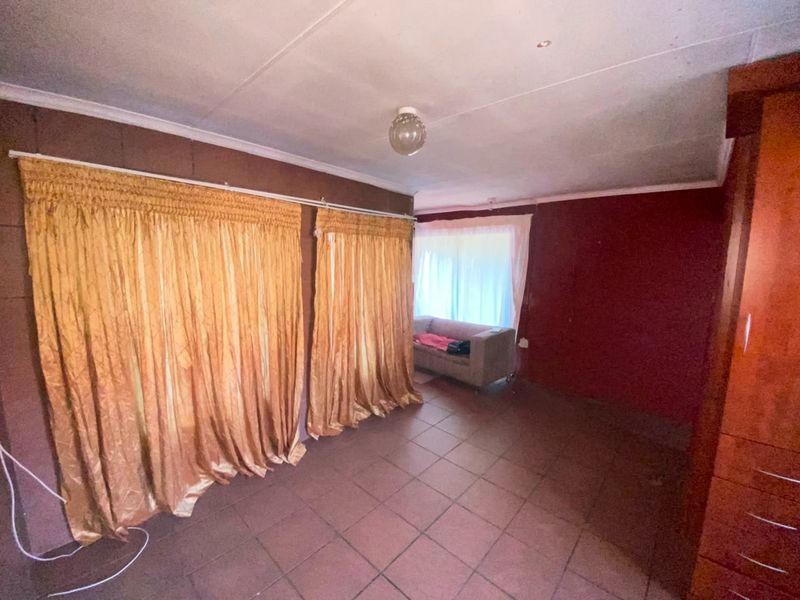 A bedroom featuring tiled flooring and built-in cupboards, currently requiring cosmetic updates to modernize the space.
