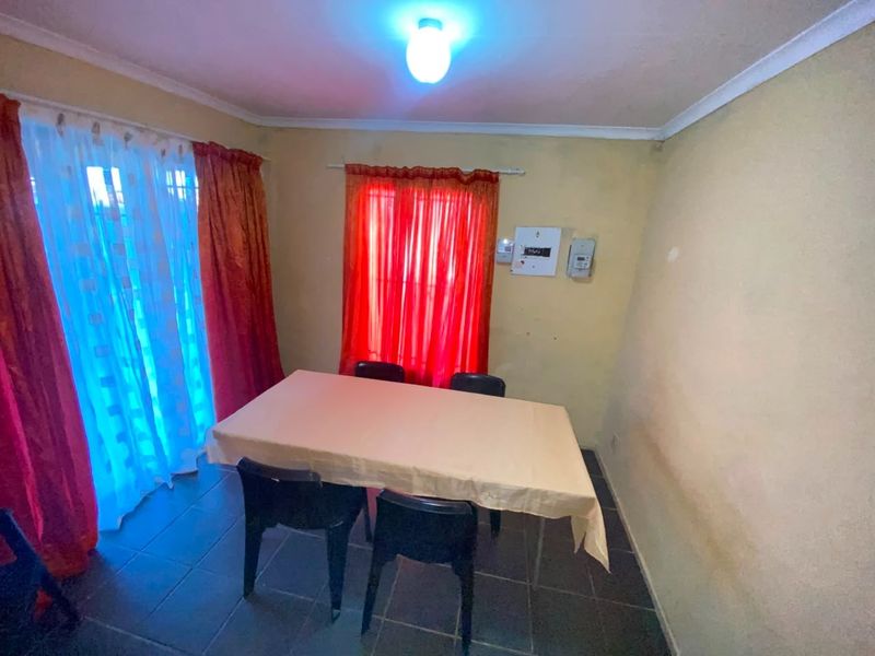 A dining area featuring tiled flooring and a wall-mounted electrical distribution board, requiring cosmetic updates to improve the overall aesthetic.