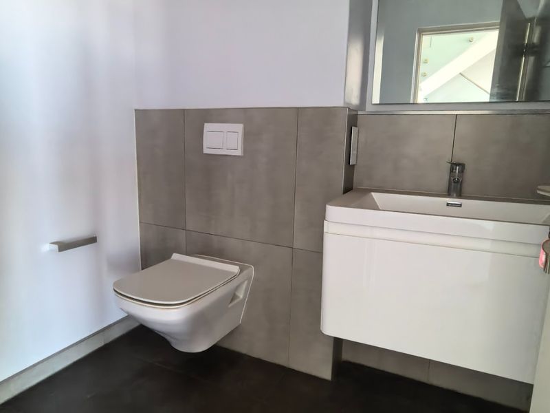 Modern guest bathroom featuring a wall-hung toilet with concealed cistern and a sleek wall-mounted vanity unit with basin.