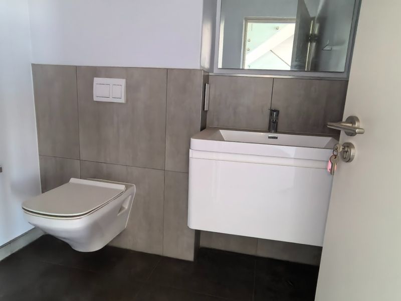 Modern guest bathroom featuring a wall-hung toilet with concealed cistern and a sleek wall-mounted vanity unit with integrated basin.