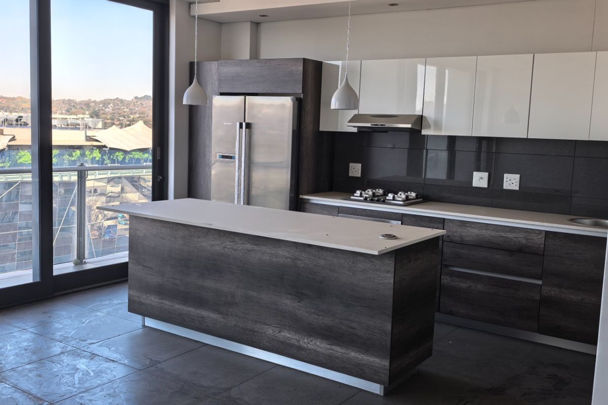 Modern kitchen featuring dark wood and white cabinetry, stone countertops, a central island, and integrated appliances with access to a balcony.