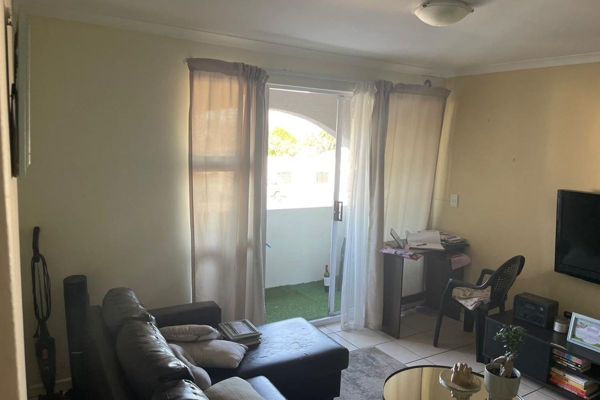 A living room featuring tiled flooring and a sliding glass door providing access to a balcony area.