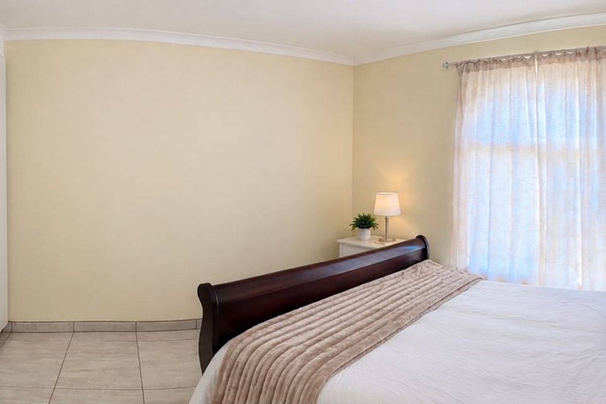 A well-maintained bedroom featuring neutral walls, tiled flooring, and ample built-in cupboard storage space.