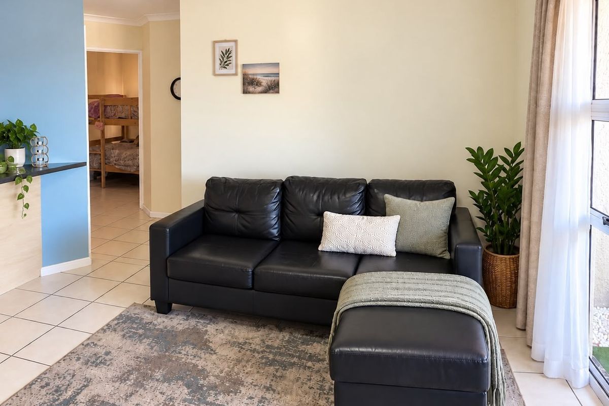 A bright living room featuring tiled flooring, cove cornicing, and a sliding glass door providing access to the exterior.