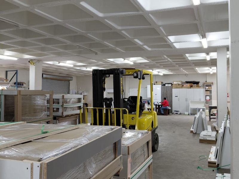 Spacious industrial warehouse area featuring a waffle slab ceiling, concrete flooring, and a roller shutter door, suitable for storage or light manufacturing operations.