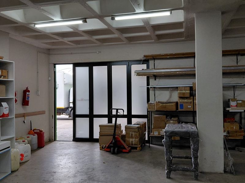 Functional industrial utility space featuring a waffle slab ceiling, concrete flooring, and direct access through a large black-framed glass door.