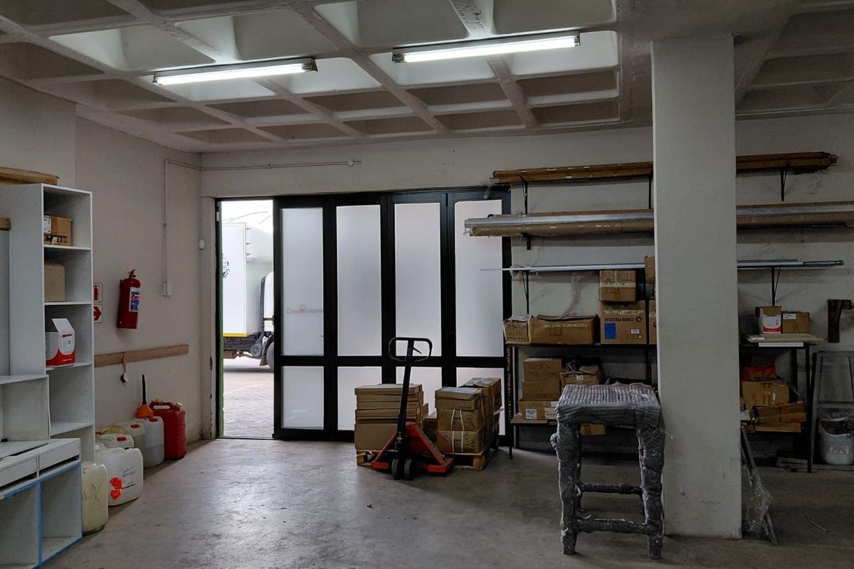 Functional industrial utility space featuring a waffle slab ceiling, concrete flooring, and direct access through a large black-framed glass door.