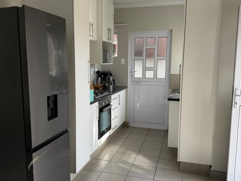 A functional kitchen featuring white cabinetry, tiled flooring, a built-in oven and hob, and a classic stable door leading to the exterior.