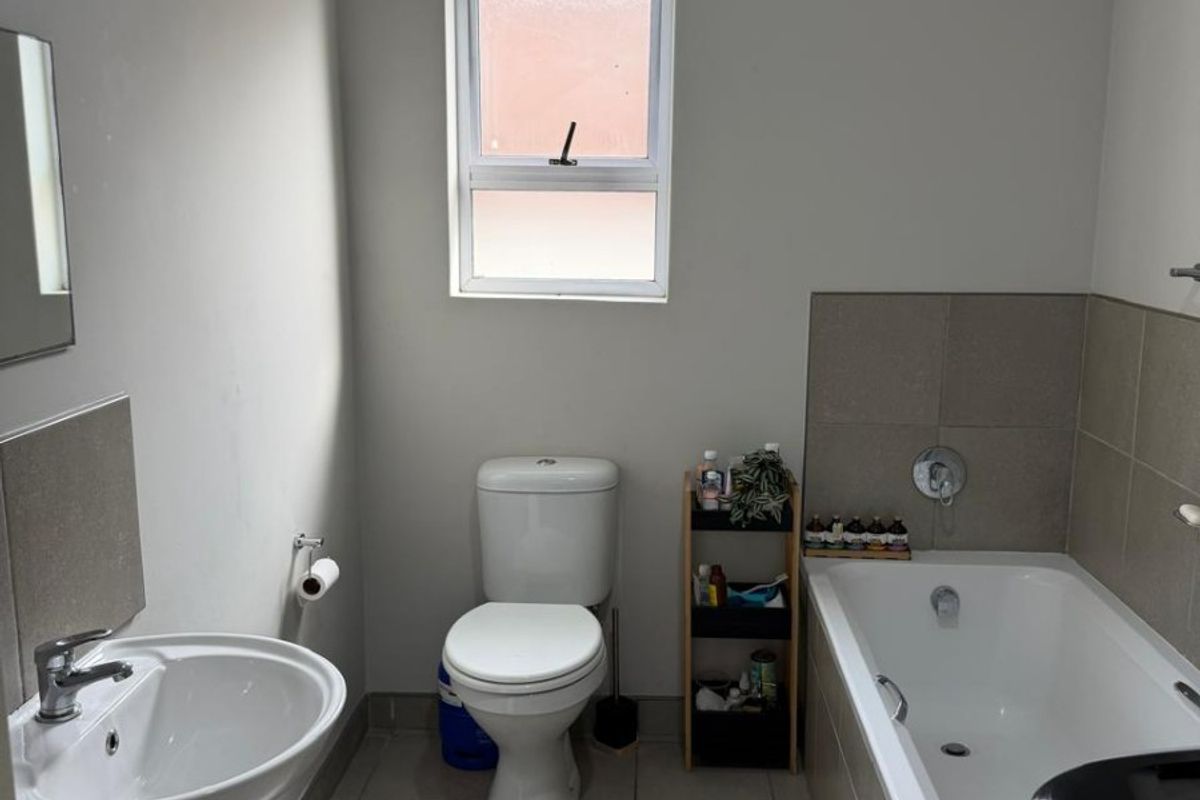 A functional bathroom featuring a pedestal basin, toilet, and bathtub with tiled splashbacks and flooring.