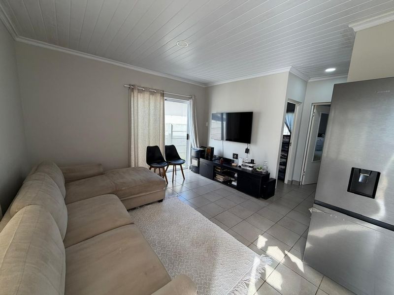 Open plan living area featuring tiled flooring, a tongue and groove ceiling, and a sliding glass door providing access to the exterior.