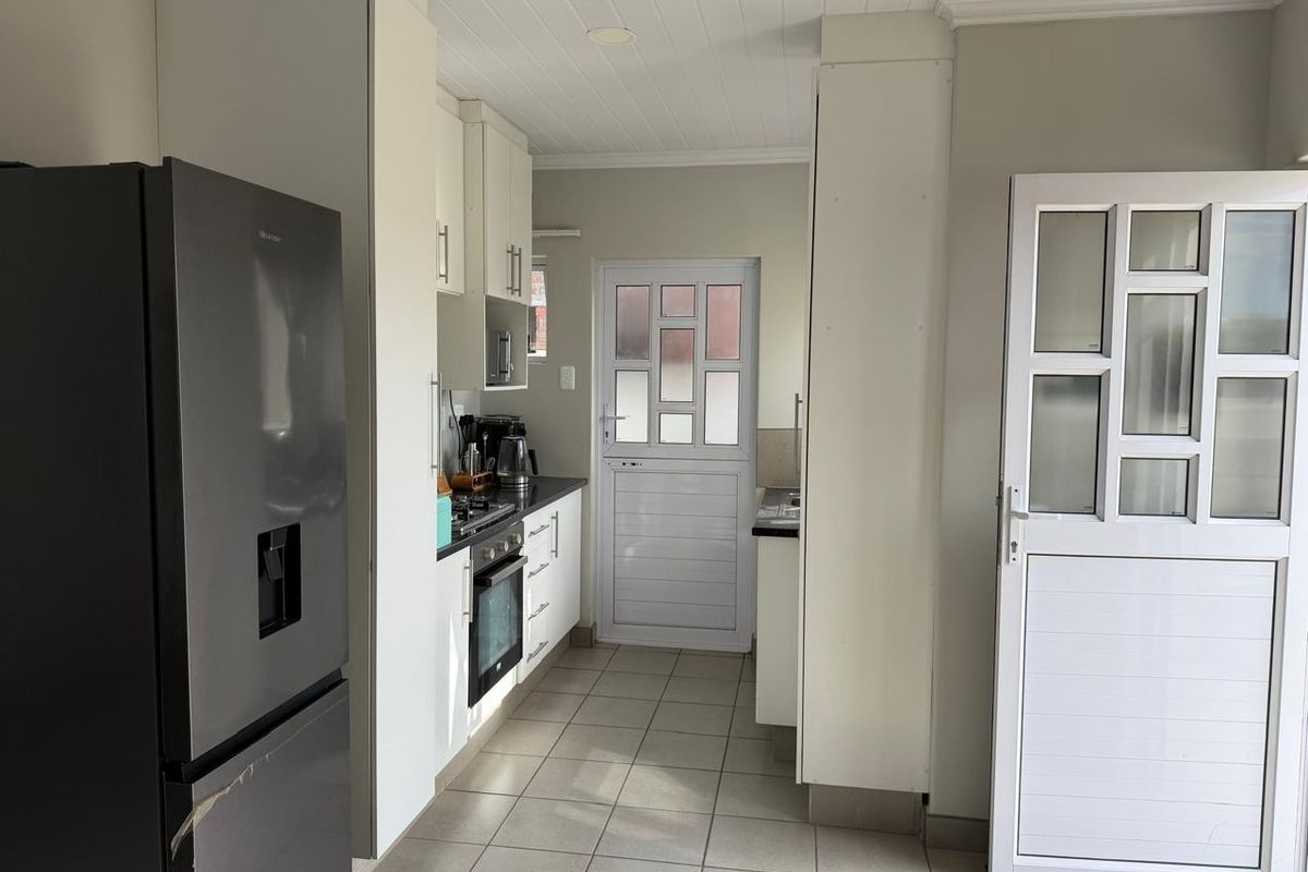 A functional kitchen featuring white cabinetry, tiled flooring, built-in oven and hob, and direct access to the exterior.