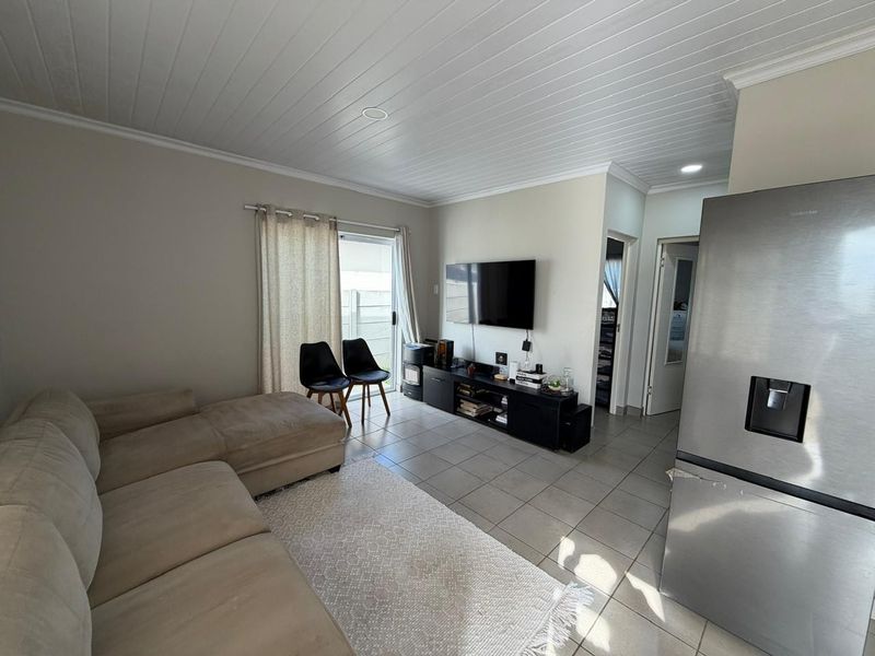 Open-plan living area featuring tiled flooring, a tongue and groove ceiling, and a sliding glass door providing access to the exterior.