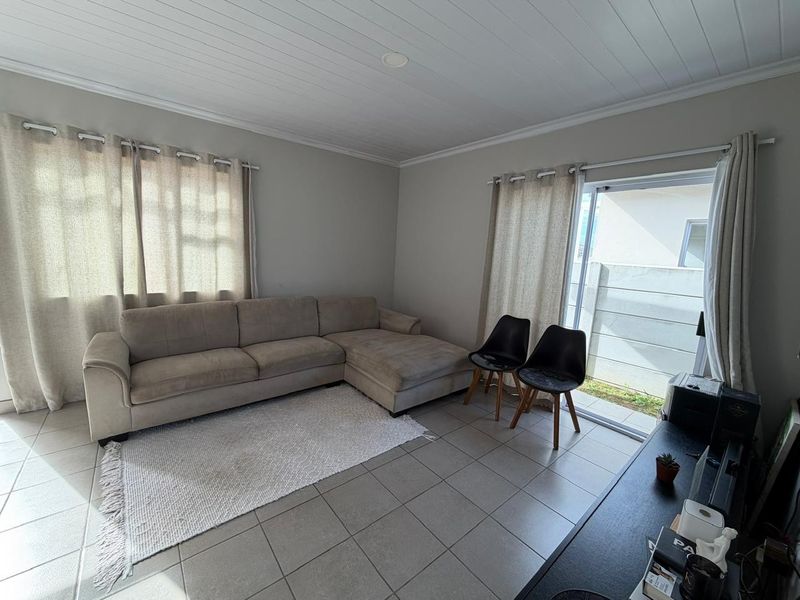 A living room featuring tiled flooring, a tongue and groove ceiling, and a sliding glass door providing access to the exterior.