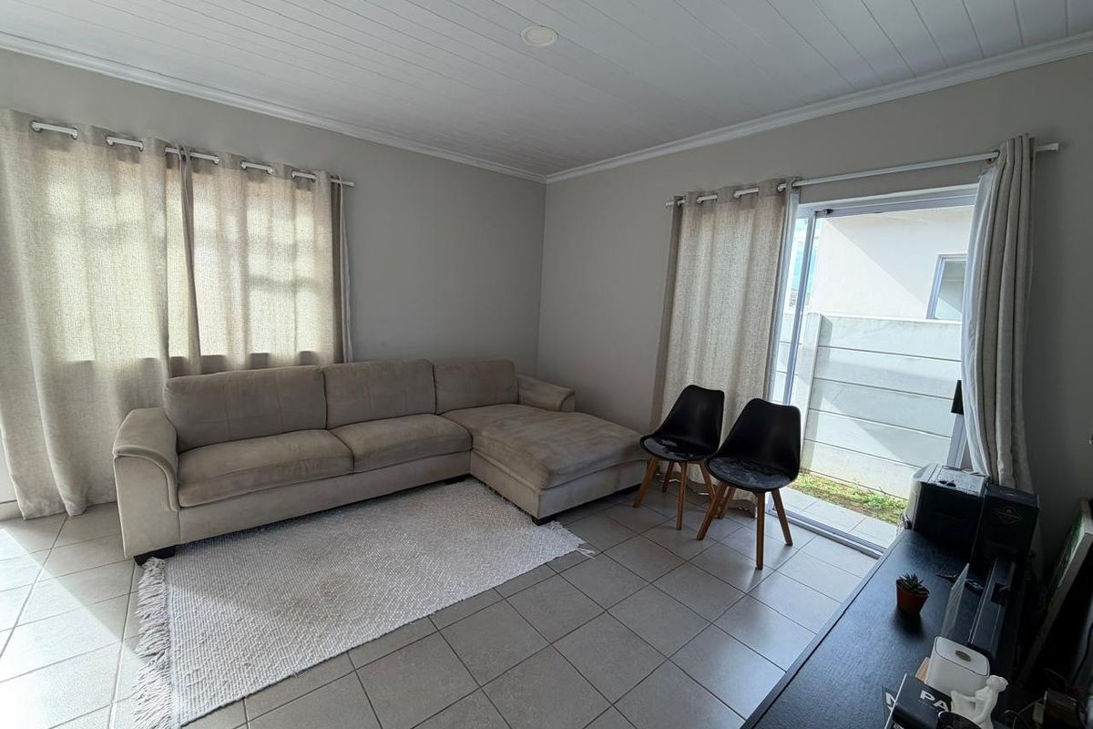 A living room featuring tiled flooring, a tongue and groove ceiling, and a sliding glass door providing access to the exterior.