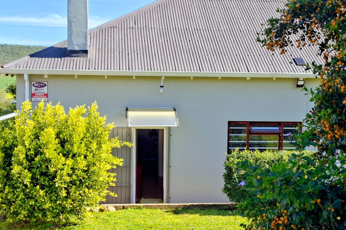 Rear view of the property featuring a corrugated metal roof, chimney, and a secure entrance with an awning.