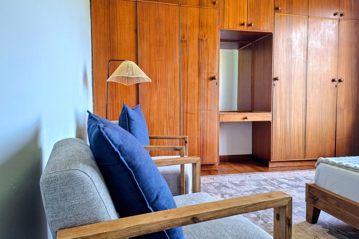 A bedroom featuring extensive floor-to-ceiling built-in wooden cabinetry with an integrated vanity area and warm hardwood flooring.