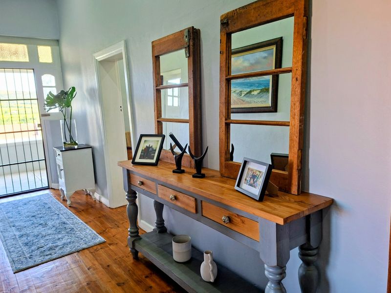 A welcoming entrance hall featuring warm timber flooring and a secure glass-panelled door leading to the exterior.