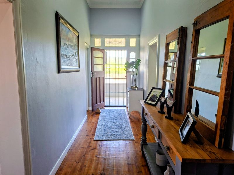 Welcoming entrance hall featuring polished hardwood flooring, a classic timber front door, and a security gate with transom window detail.
