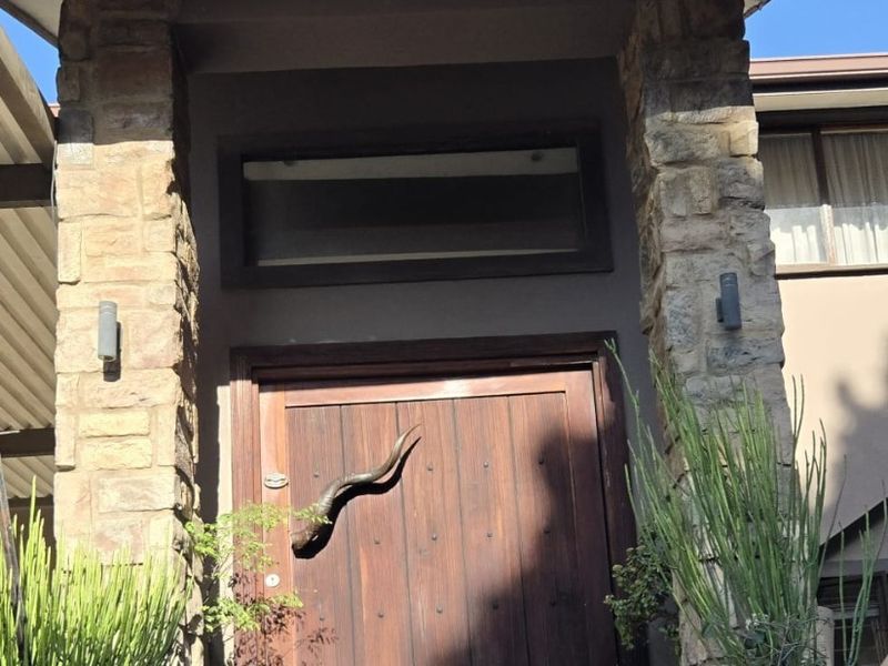 A welcoming front entrance featuring a solid timber door, stone-clad pillars, and tiled steps under a covered porch.