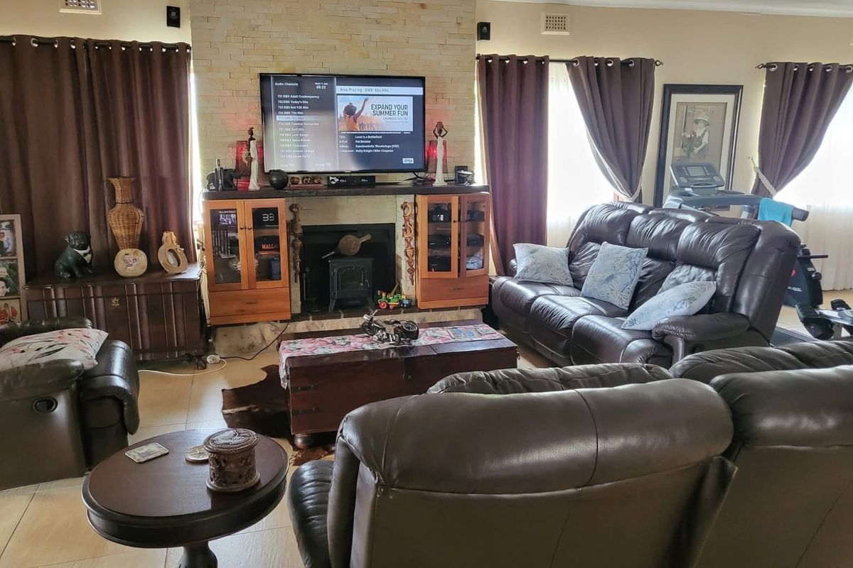 Spacious living room featuring a prominent stone-clad fireplace with a built-in wood-burning stove and integrated cabinetry, finished with neutral tiled flooring.