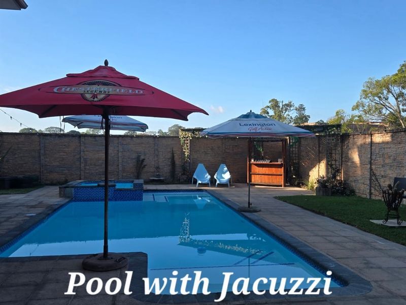 Outdoor pool area featuring an integrated jacuzzi, paved decking, and a perimeter boundary wall, providing a private space for relaxation and entertainment.
