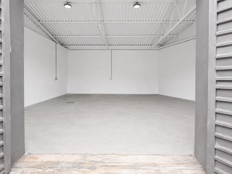 A clean, spacious industrial utility area featuring painted brick walls, a concrete floor, and exposed steel roof trusses with industrial lighting.