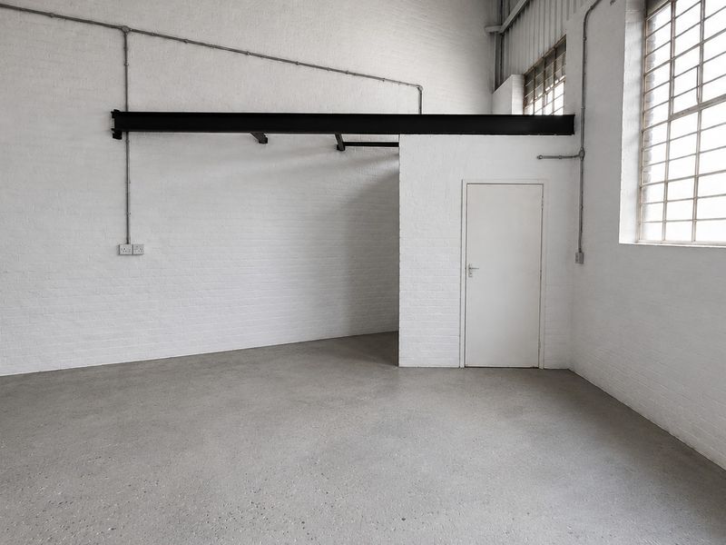 A clean, industrial-style open utility space featuring exposed brick walls, polished concrete flooring, and large grid windows providing ample natural light.