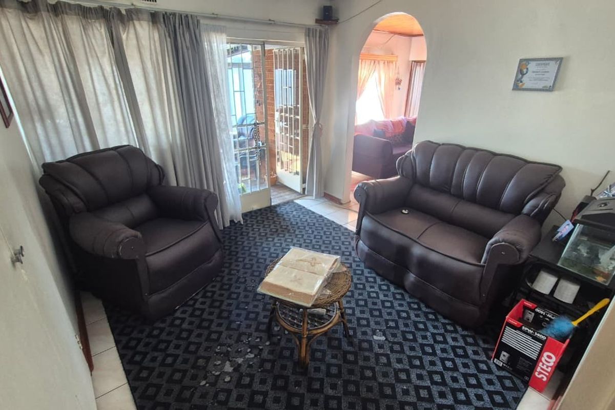 A living room area featuring tiled flooring, an arched entryway, and a sliding glass door providing access to the exterior.