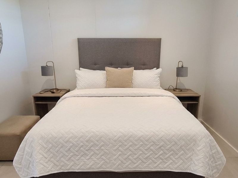 A well-maintained bedroom featuring neutral tiled flooring and a high-level window providing natural light.