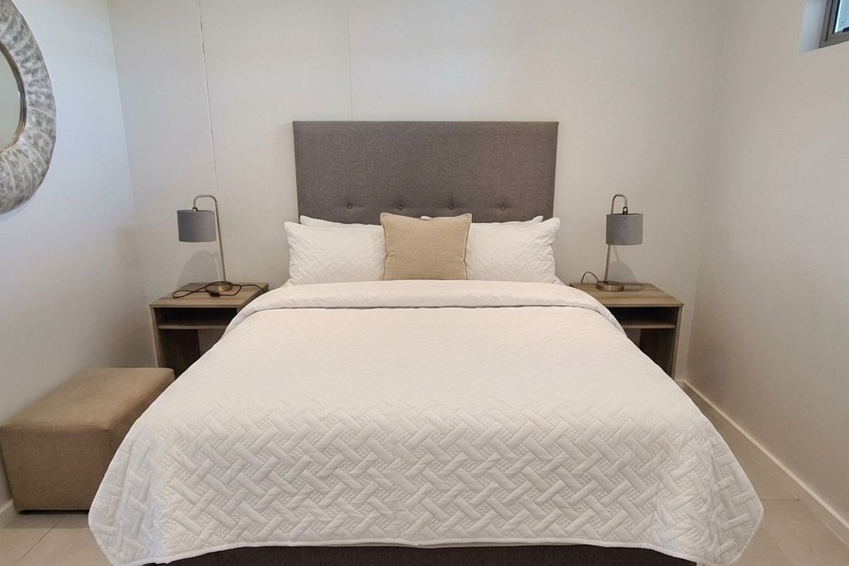 A well-maintained bedroom featuring neutral tiled flooring and a high-level window providing natural light.