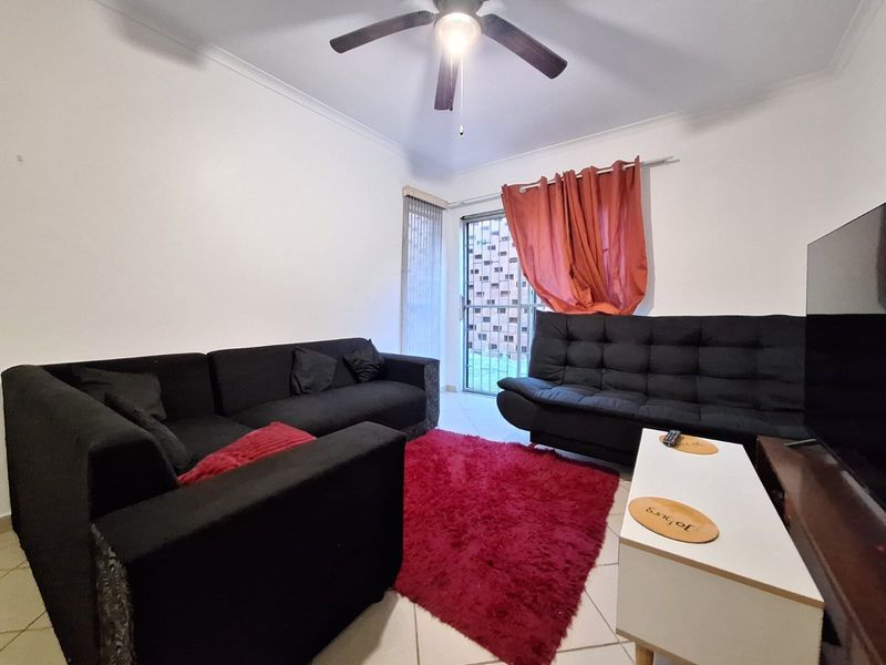 A living room featuring tiled flooring, a ceiling fan, and a sliding glass door providing access to the exterior.