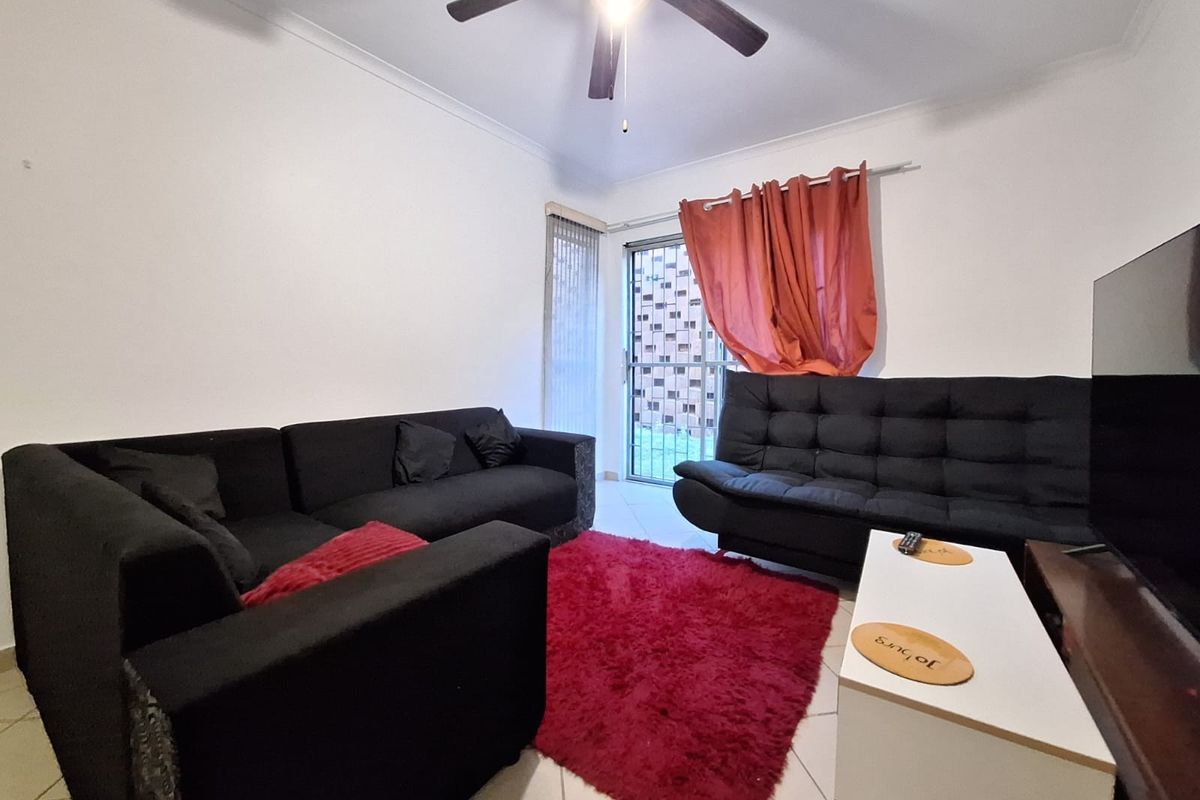 A living room featuring tiled flooring, a ceiling fan, and a sliding glass door providing access to the exterior.