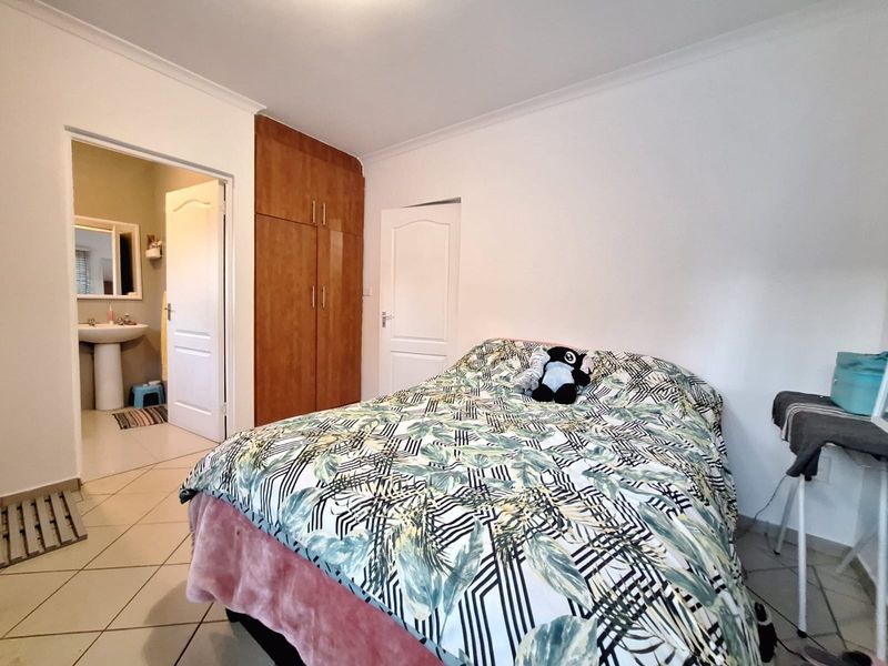 A bedroom featuring tiled flooring, a built-in wooden wardrobe, and direct access to an en-suite bathroom.