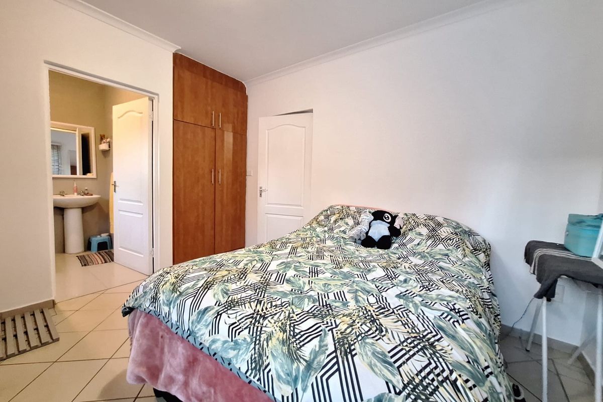 A bedroom featuring tiled flooring, a built-in wooden wardrobe, and direct access to an en-suite bathroom.
