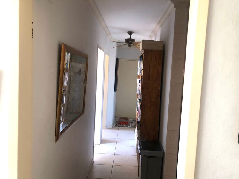 A functional hallway featuring tiled flooring, ceiling fan, and decorative cornicing, providing access to other areas of the apartment.