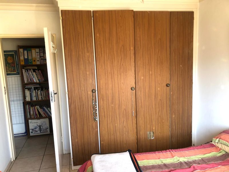 A bedroom featuring a large built-in wooden wardrobe with visible wear and damage to the lower door panel.