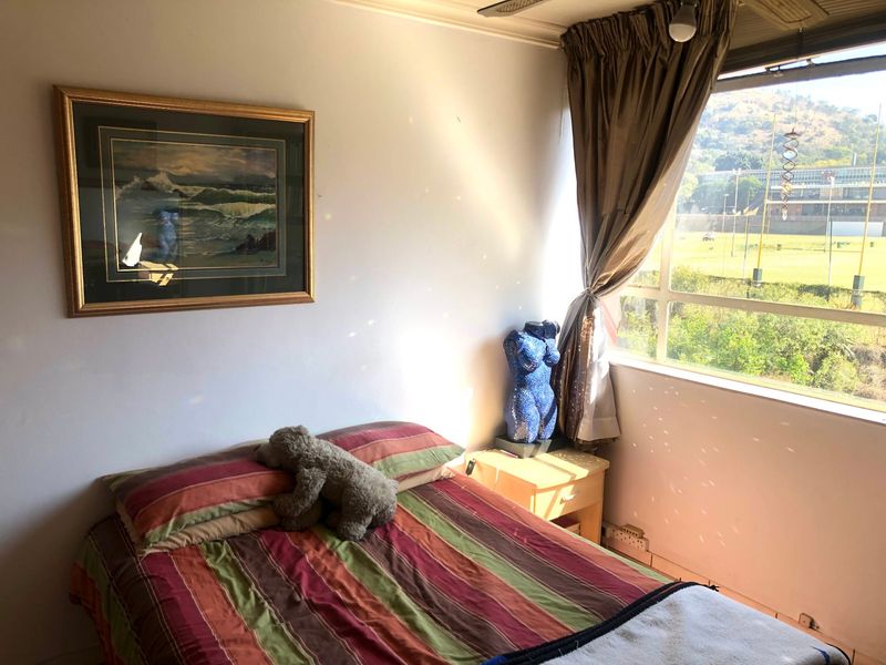 A bedroom featuring a large window with natural light and views, providing a functional space for rest.
