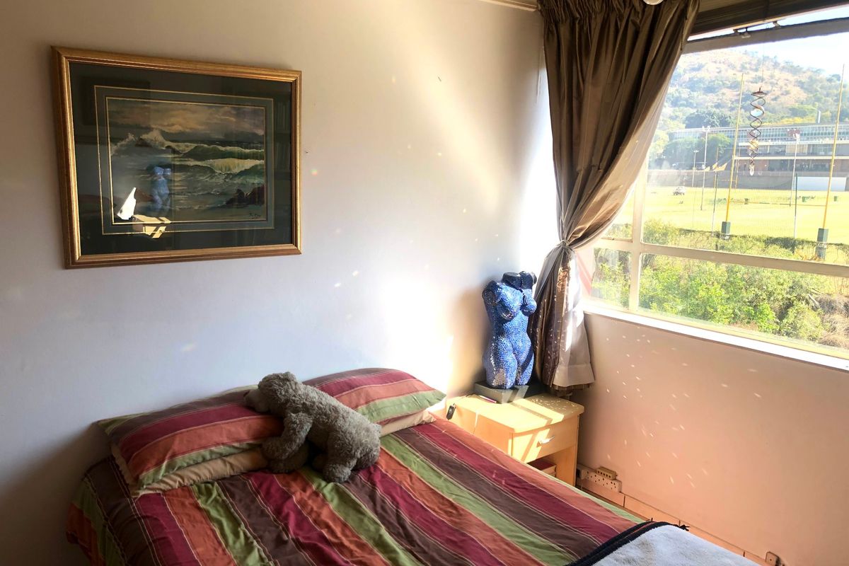 A bedroom featuring a large window with natural light and views, providing a functional space for rest.